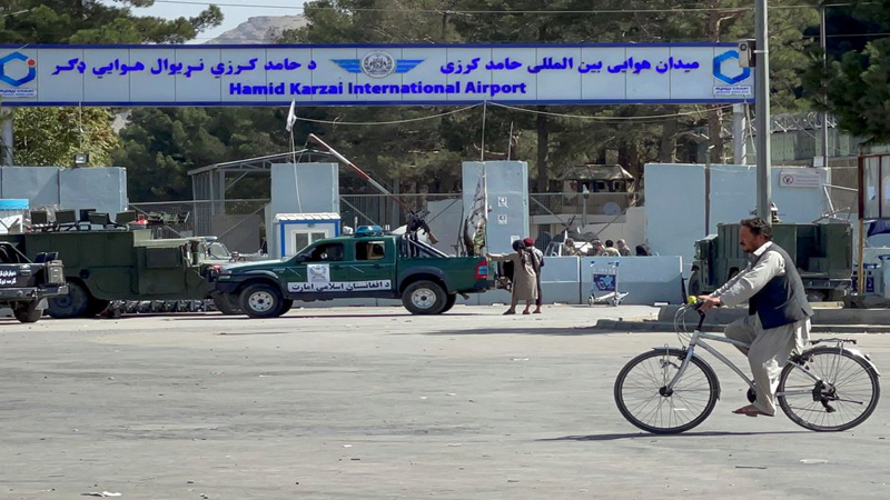 Taliban stand at the entrance gate of Hamid Karzai International airport while Taliban forces block the roads around the airport after yesterday