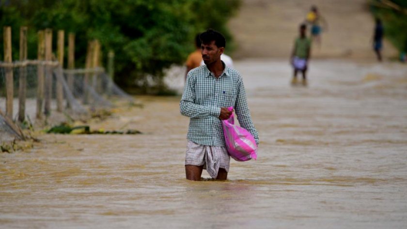 A Villager wades through a flooded road in Hojai district of India