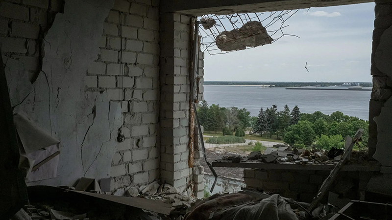 A partial view of the Kakhovka dam and its reservoir as seen on Thursday from a destroyed apartment in Vesele, a village in the Kherson region of southern Ukraine. Mauricio Lima for The New York Times